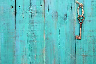 Bronze skeleton key hanging on vintage teal blue wood door