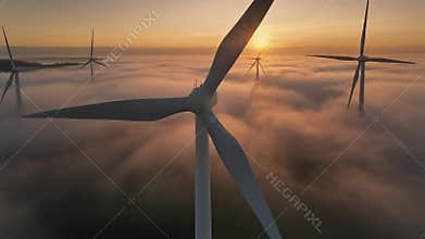 Drone shot wind turbine during sunrise dense morning fog. Close-up Wind turbines. Windmills