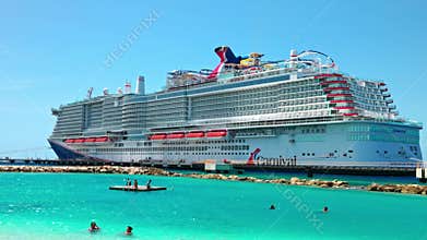 Beautiful view of Carnival cruise ship near tropical beach with people swimming in clear turquoise Caribbean Sea.