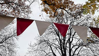 Red and white triangular bunting hanging against a background of bright yellow autumn foliage and sky