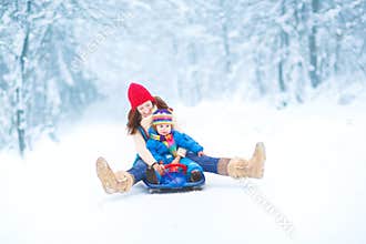 Young mother and toddler daughter enjoying sledge