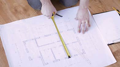 Close up of male hands measuring blueprint