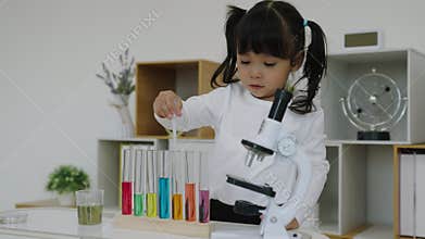 toddler girl scientist study using pipette dropping liquid with test tube and beaker