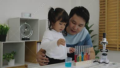 toddler girl scientist study using pipette dropping liquid with test tube and beaker. learning science with father