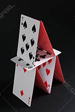 House of playing cards on black background