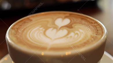 Close up of freshly made latte art with heart design in a white cup