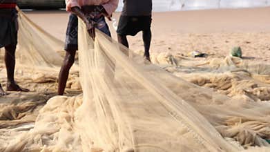 Fishermen checking and collecting the fishing nets for repairs.