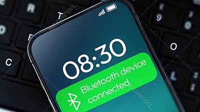 Smartphone screen at 0830 showing Bluetooth device connected notification on green banner placed over a black computer keyboard