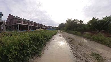 puddle along the diminishing perspective rural pathway into the rural countryside by the construction site.