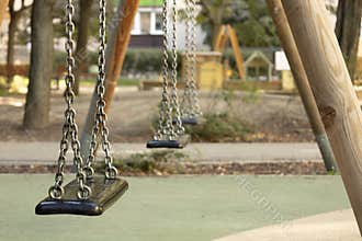 Empty swing seat in a quiet playground on a sunny autumn day