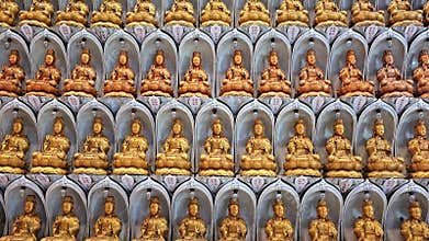 Rows of identical golden Buddha statues in arched niches at Kek Lok Si Temple, Penang. Multiple Guanyin deity sculptures arranged