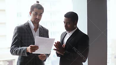 Portrait of African american and caucasian European young businessmen discussing data from documents