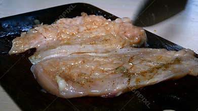 Chefs hand is beaten raw chicken steak with kitchen knife for cooking tasty beefsteak. Close-up.