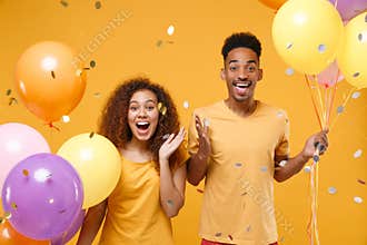 Excited young friends couple african american guy girl in casual clothes isolated on yellow background. Birthday holiday
