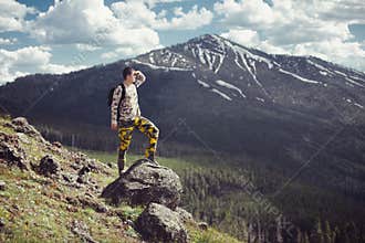 Excited man hiking on a mountain top with backpack enjoy the view and looking for adventures.