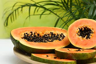 Plate with fresh juicy cut papayas on white table against blurred background