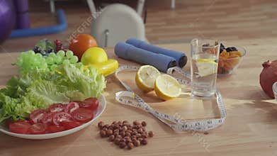 Concept of proper nutrition ,on the table are dumbbells measuring tape vegetables fruits and nuts