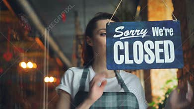 Business owner hanging we`re open sign on front door smiling welcoming clients