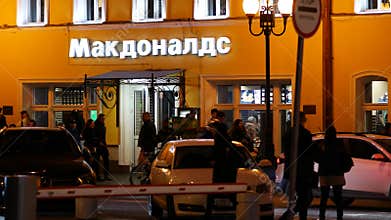 People walk past the McDonald`s fast food restaurant on Arbat street in the city center. Luminous sign. Nightlife in the capital.