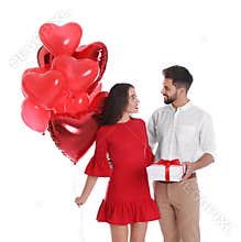 Happy young couple with gift box and heart shaped balloons isolated. Valentine`s day celebration