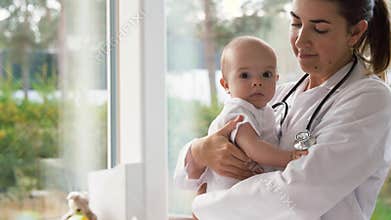 Female pediatrician doctor taking baby at clinic