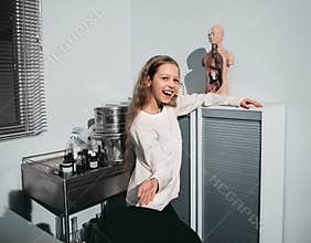 Cheerful schoolgirl girl standing in the office of the school nurse
