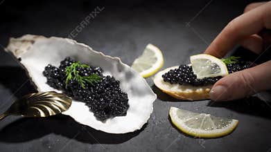 Woman takes a sandwich with black caviar. Caviar on a oyster shell on a plate
