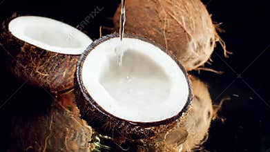 Closeup slow mtoion video of water droplets slowly falling and pouring in coconut halves. Perfect abstract shot for