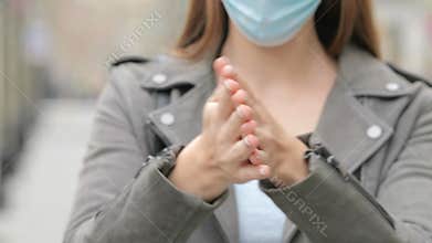 Girl with mask cleaning hands with alcohol sanitiser