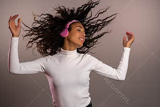 Mixed race girl with curly afro hair having fun,smiling, dancing with headphones