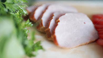 Piece of cooked ham and greens on a wooden surface. Selective focus. Close up