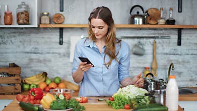 Smiling woman cooking food check vegetables look at smartphone. Shot on RED Raven 4k Cinema Camera