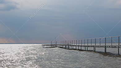 Cloudy sky over the lake Balaton in Hungary. Metal pier in the water