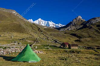 Green tent in an empty camping at the bottom of beautiful snow mountain