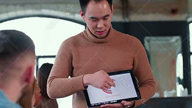 Young professional happy Asian finance coach businessman using digital tablet chart leading team meeting at loft office.