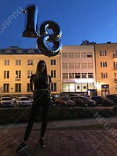 Girl celebrating her 18 birthday, standing with balloons.