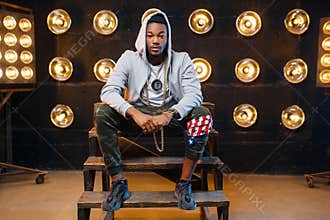 Black rapper in hoodie sitting on the steps