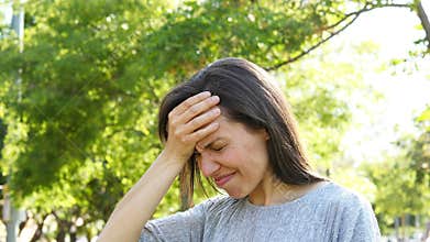 Adult woman suffering head ache in a park