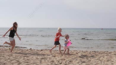 Mother with children playing on the beach by the sea
