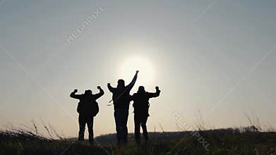 Climbing the mountains at sunset. Tourists help each other by giving a hand. Help in the mountains and teamwork in