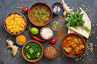 Assorted various Indian food on a dark rustic background. Traditional Indian dishes - Chicken tikka masala, palak paneer, saffron