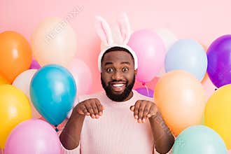 Photo of funny dark skin guy colorful decorations easter party hold arms like rabbit paws obedient person wear sweater