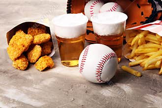 Chicken nuggets and french fries on the table with draft beer. Baseball party food with balls for the playoffs