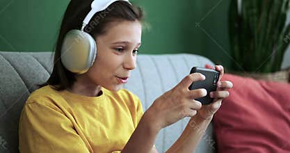 Schoolboy in Headphones Playing on Phone and Expressing Amazement on Couch