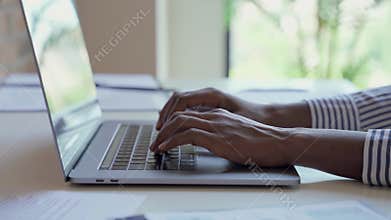 Young African black female hands typing on laptop computer keyboard.