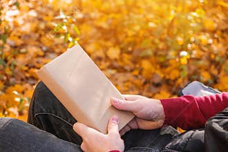 A man holds book with an empty space in the autumn nature. Book copy space. The concept of reading books in nature. Free