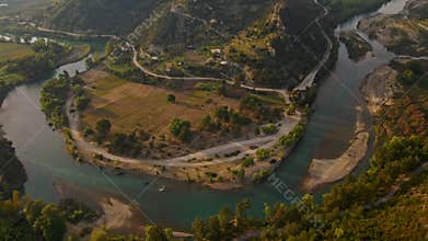 aerial scenic landscape with green fields, meadows, curved mountain river and mountain ridge with high mountains and