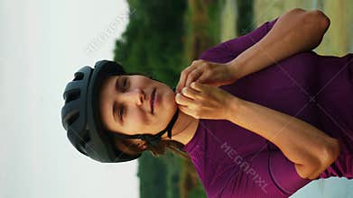Woman puts on cycling helmet. Cyclist putting on helmet. Vertical concept