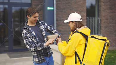 Caucasian Bike Courier Lady Delivering the Paper Box to the Happy Guy Near His Home. The Client Signs for Delivery on