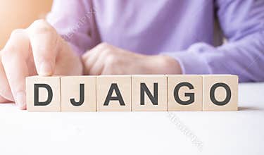Businessman hand holding wooden cube block with DJANGO business word on table background